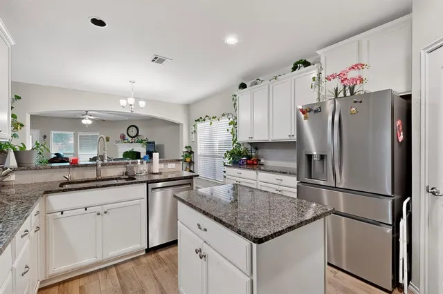 a kitchen with granite countertop a refrigerator and a sink