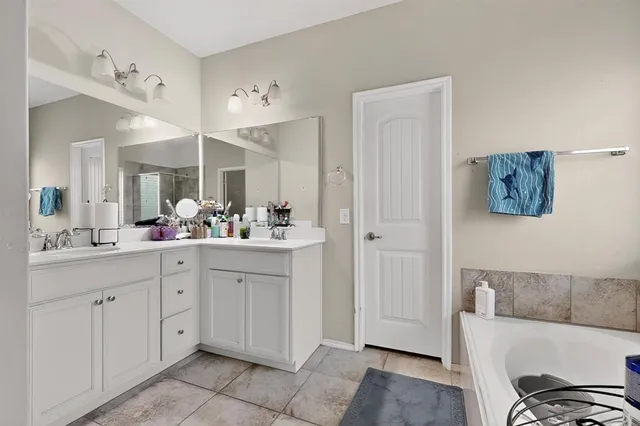 a spacious bathroom with a tub sink and mirror