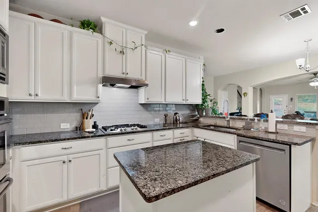 a kitchen with granite countertop a sink a stove and cabinets
