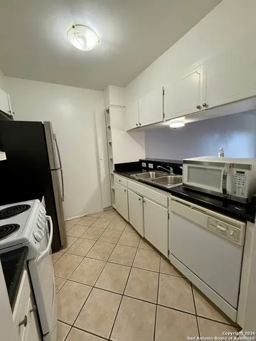 a kitchen with stainless steel appliances a sink a stove a refrigerator and cabinets