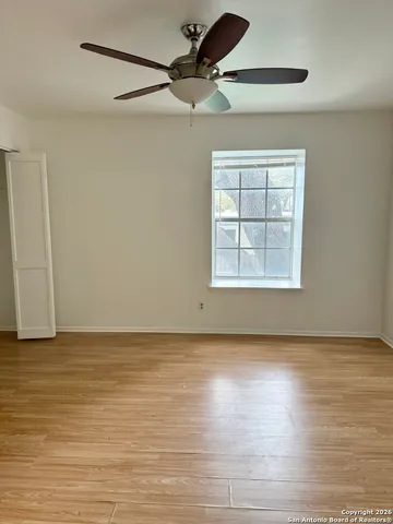 a view of an empty room with a window and wooden floor