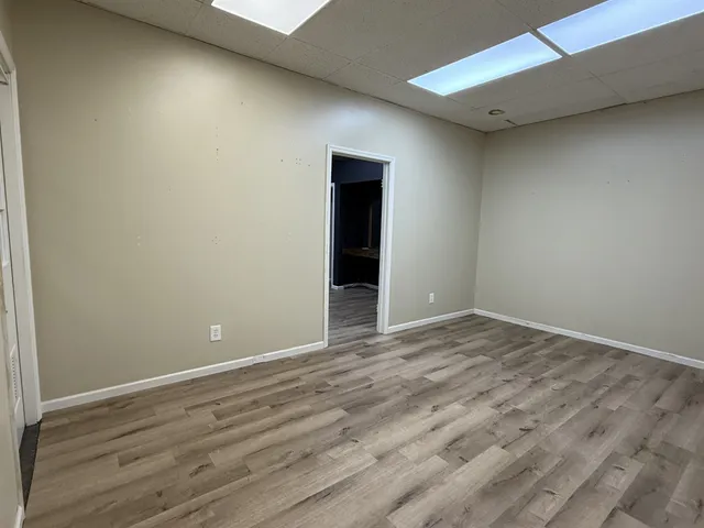 a view of an empty room with wooden floor and closet