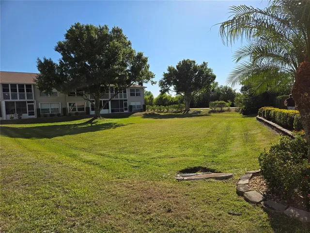 a view of a swimming pool with a yard and palm trees