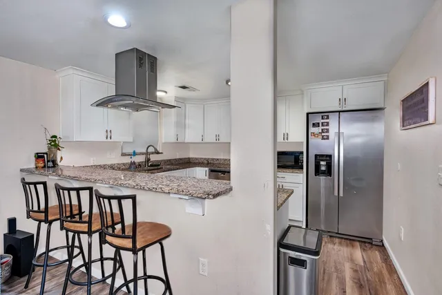 a kitchen with stainless steel appliances kitchen island granite countertop a table chairs refrigerator and microwave