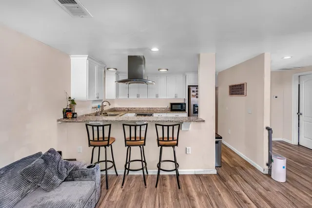 a kitchen with granite countertop a refrigerator sink and white cabinets