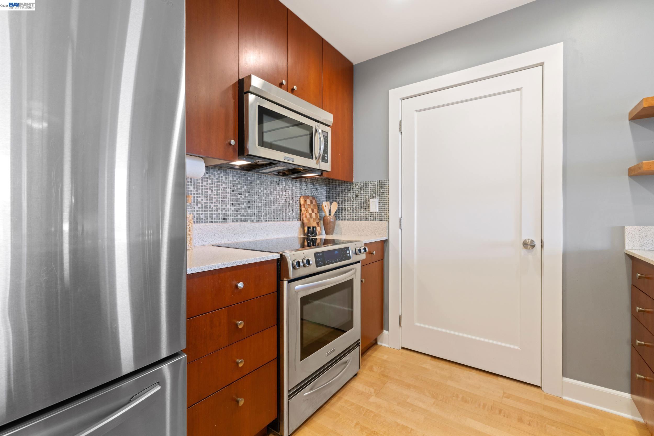 585 Ninth Street, Unit 443 Oakland, CA 94607 - Photo 7 of 32 a kitchen with stainless steel appliances granite countertop a refrigerator and a stove top oven