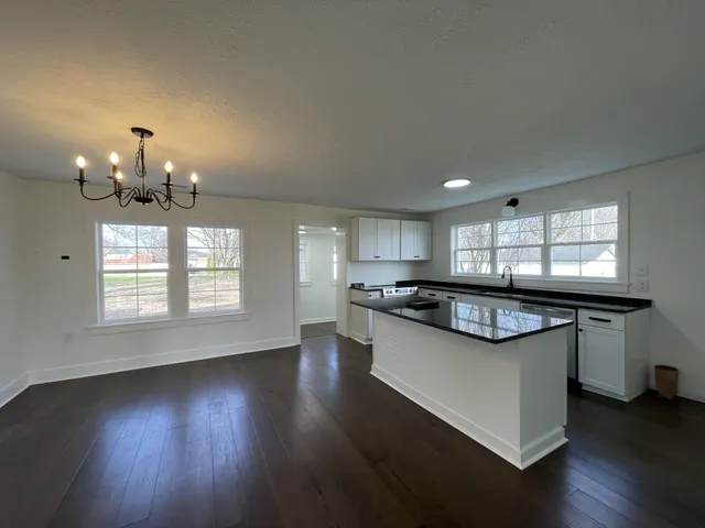 a kitchen with kitchen island granite countertop a sink cabinets and wooden floor
