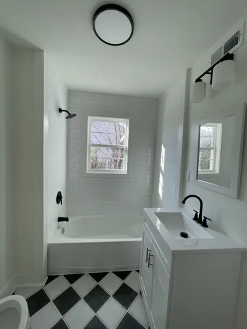 a bathroom with a bathtub sink and mirror
