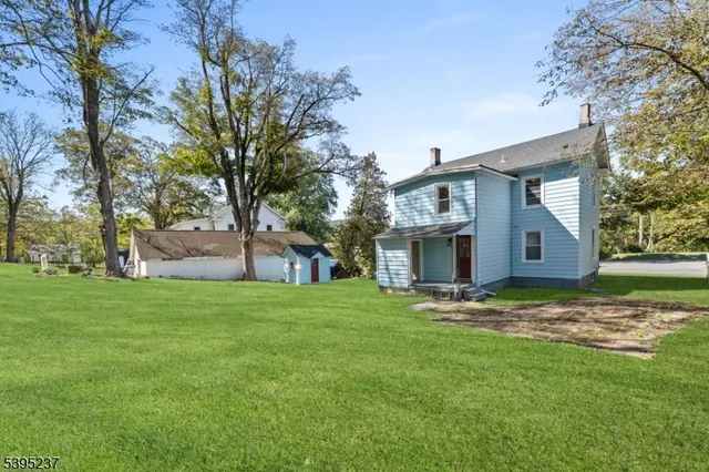 a house that is sitting in the grass with large trees