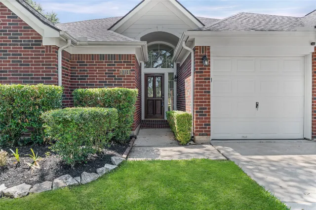 a view of a house with a big yard plants and large tree
