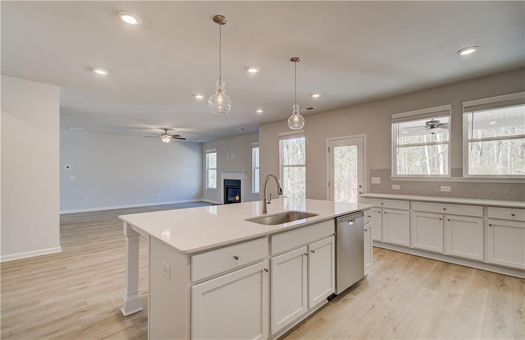 228 Ruthe Cove Locust Grove, GA 30248 - Photo 14 of 31 a large white kitchen with a sink and dishwasher with wooden floor