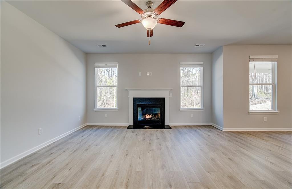 228 Ruthe Cove Locust Grove, GA 30248 - Photo 9 of 31 an empty room with windows a fireplace and wooden floor