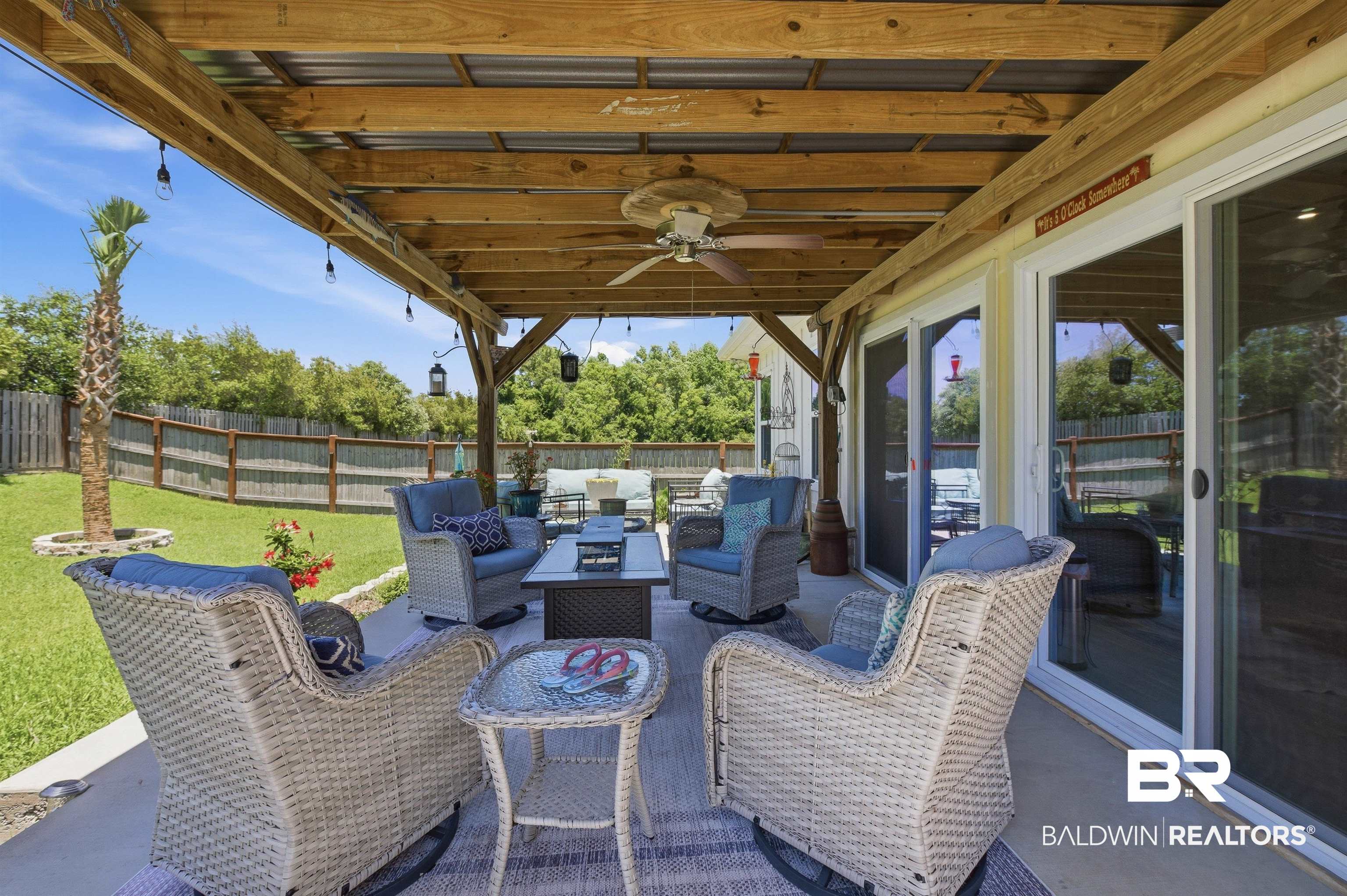 8735 Bronze Lane Foley, AL 36535 - Photo 42 of 58 Spacious covered patio featuring a wood beam roof structure, ceiling fan, string lighting, and multiple sliding glass doors for interior access