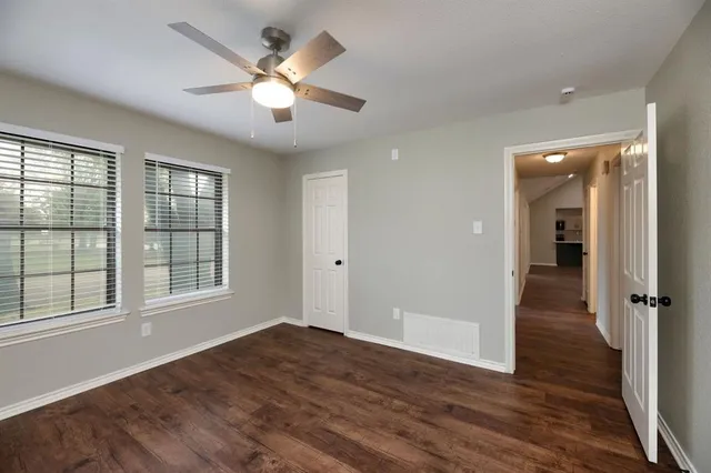 a view of a livingroom with a fan a large window with wooden floor