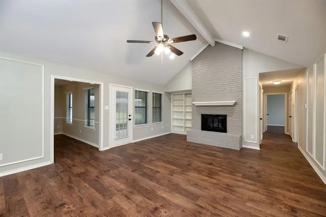 a view of an empty room with wooden floor fireplace and a window