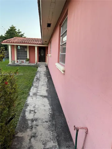 a front view of a house with a yard and potted plants