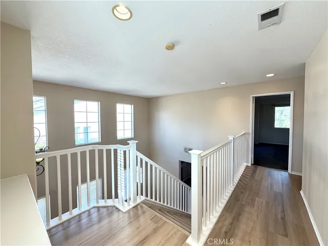 a view of a hallway with wooden floor and windows