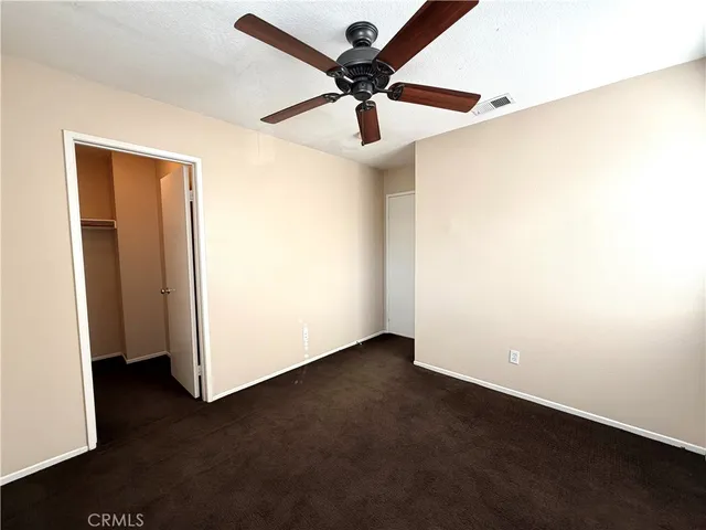 an empty room with a ceiling fan and wooden floor