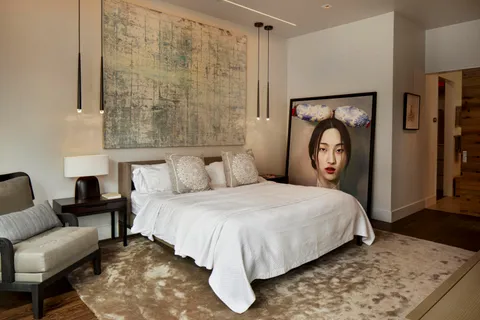 a bedroom with bed and a chair with mirror