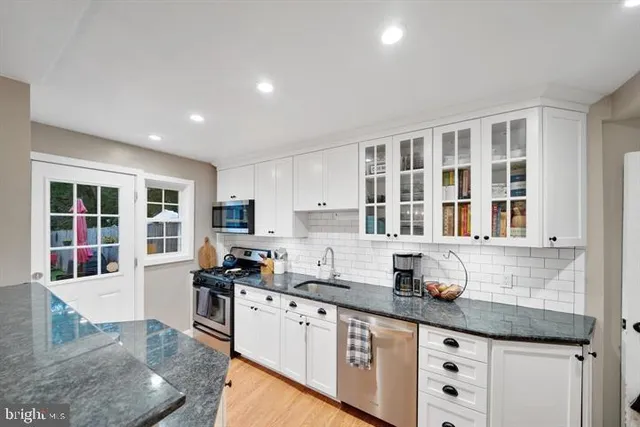 a kitchen with granite countertop white cabinets and window