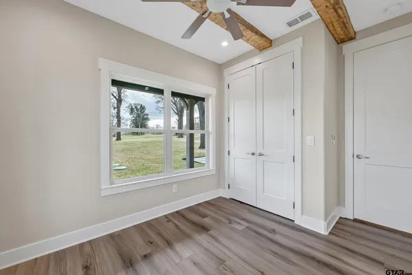 an empty room with wooden floor chandelier fan and windows