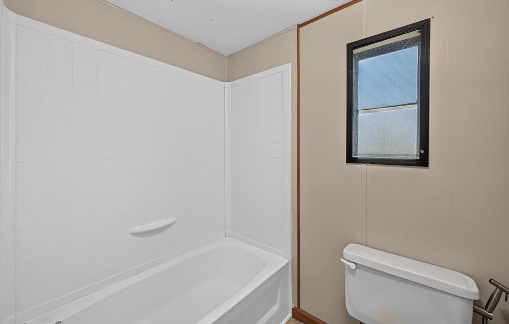 736 Little Joe Road Sanger, TX 76266 - Photo 8 of 17 Tub and shower combination featuring a white surround, integrated soap dish, and a black-framed window