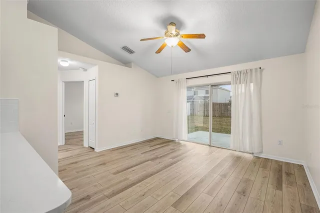 a view of an empty room with wooden floor and window