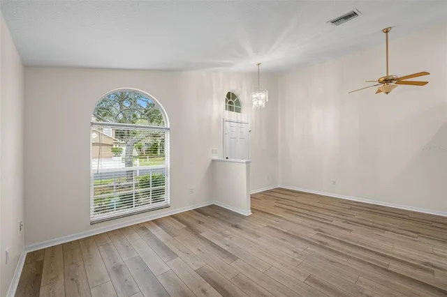 an empty room with wooden floor cabinet and windows