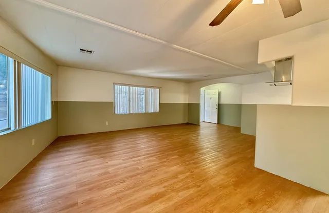 a view of an empty room with window and wooden floor
