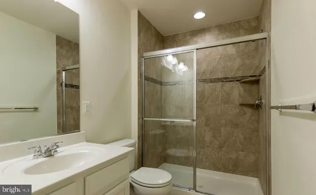 a bathroom with a shower sink vanity mirror and toilet