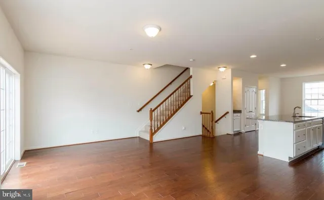 a view of an empty room with wooden floor and stairs