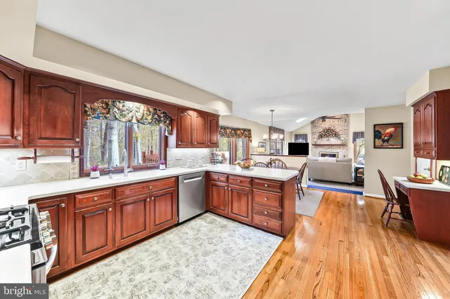 a large kitchen with stainless steel appliances granite countertop a stove top oven a sink dishwasher and wooden cabinets with wooden floor