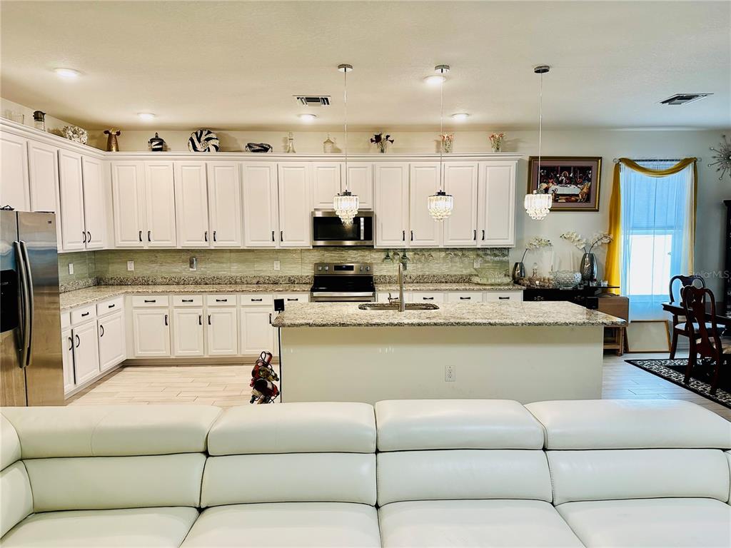 944 Old Windsor Way Spring Hill, FL 34609 - Photo 4 of 31 a living room with stainless steel appliances kitchen island granite countertop furniture and a view of kitchen
