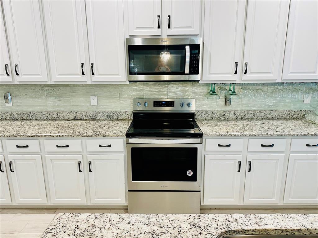 944 Old Windsor Way Spring Hill, FL 34609 - Photo 7 of 31 a kitchen with granite countertop white cabinets and stainless steel appliances
