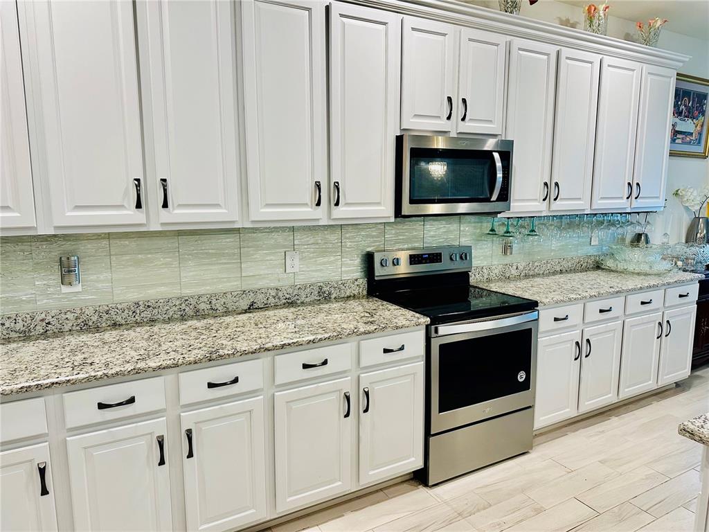 944 Old Windsor Way Spring Hill, FL 34609 - Photo 10 of 31 a kitchen with granite countertop white cabinets and white appliances