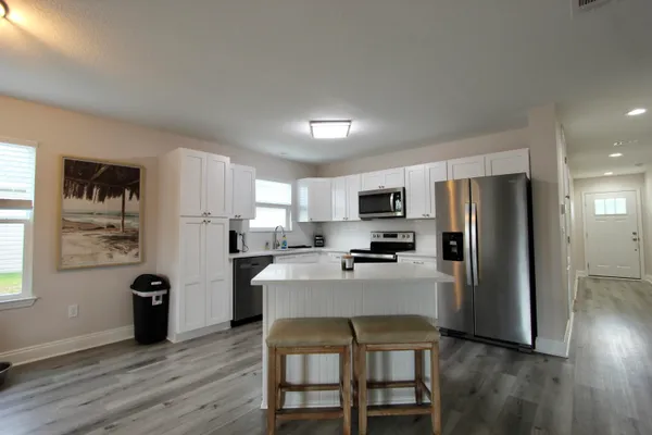 a kitchen with stainless steel appliances a refrigerator a stove a dining table and chairs