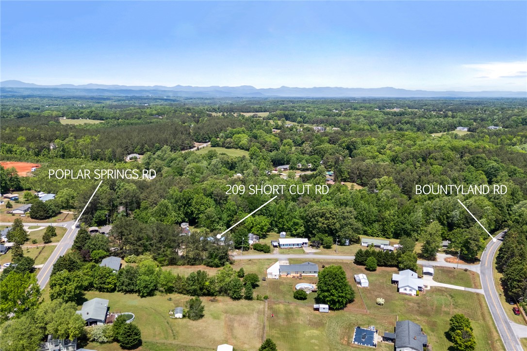 209 Short Cut Road Westminster, SC 29693 - Photo 24 of 27 An aerial perspective reveals a vast landscape with lush greenery and distant mountains under a clear sky.