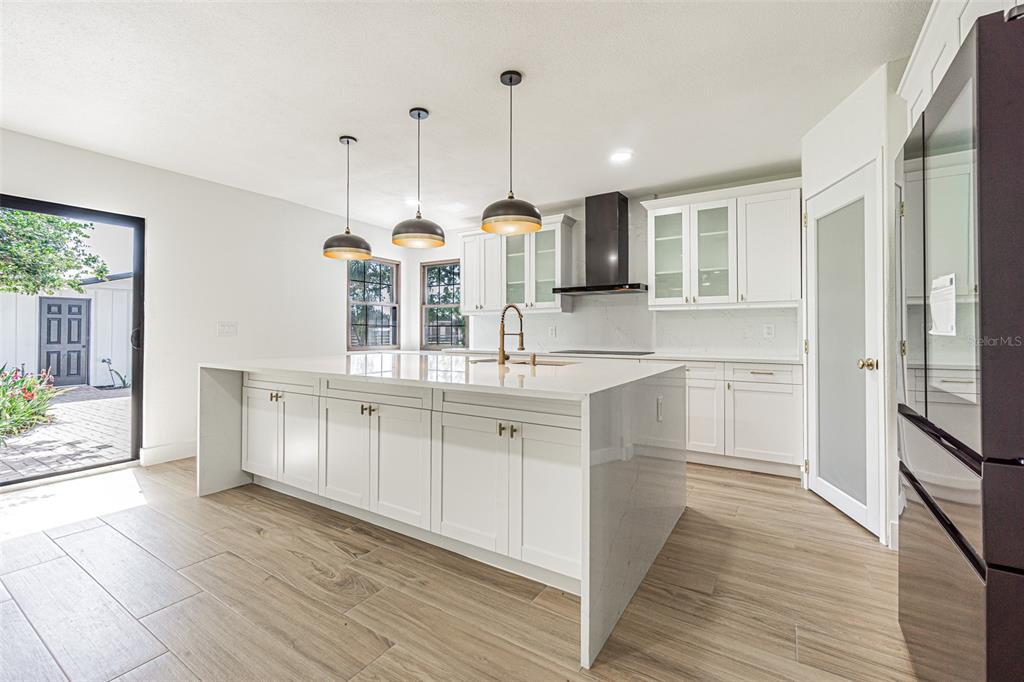 5302 Turkey Creek Road Plant City, FL 33567 - Photo 3 of 46 a kitchen with kitchen island granite countertop a stove a sink and white cabinets with wooden floor