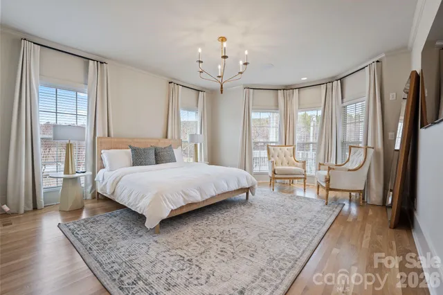 a bedroom with a large bed a chandelier and next to a window