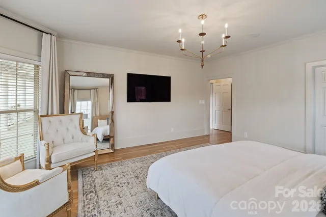 a spacious bedroom with a large bed a flat screen tv and a chandelier