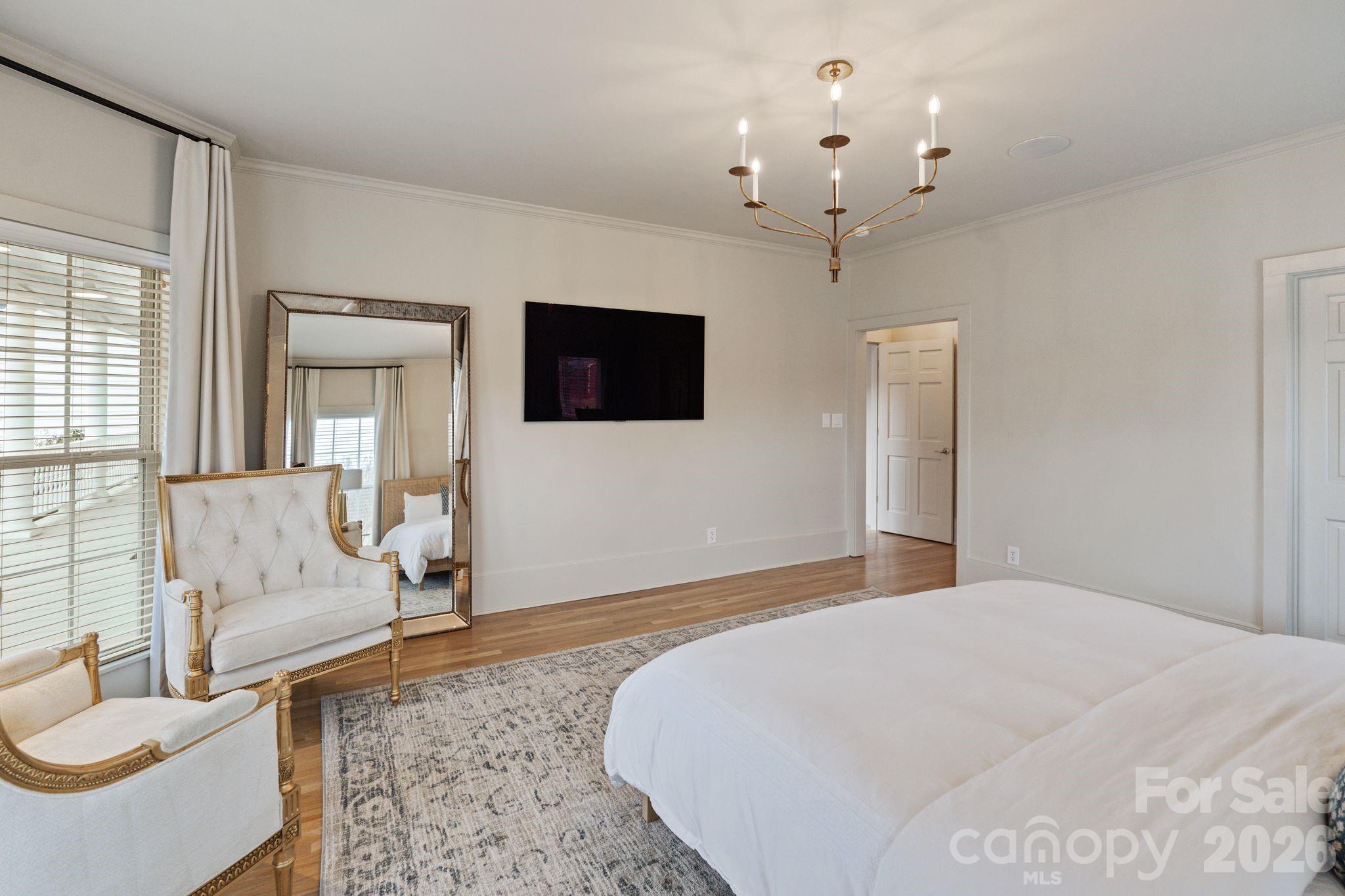 940 State Rd S-13-106 Pageland, SC 29728 - Photo 17 of 41 a spacious bedroom with a large bed a flat screen tv and a chandelier