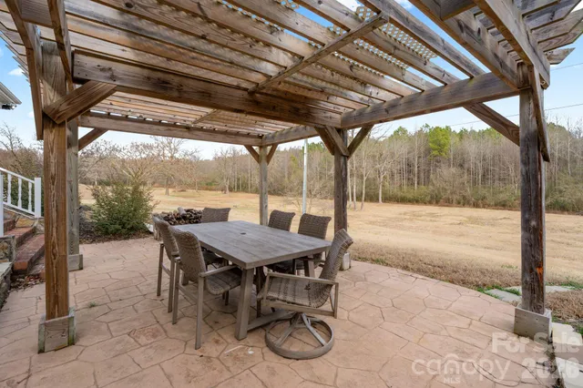 a view of a patio with table and chairs and wooden floor next to a yard