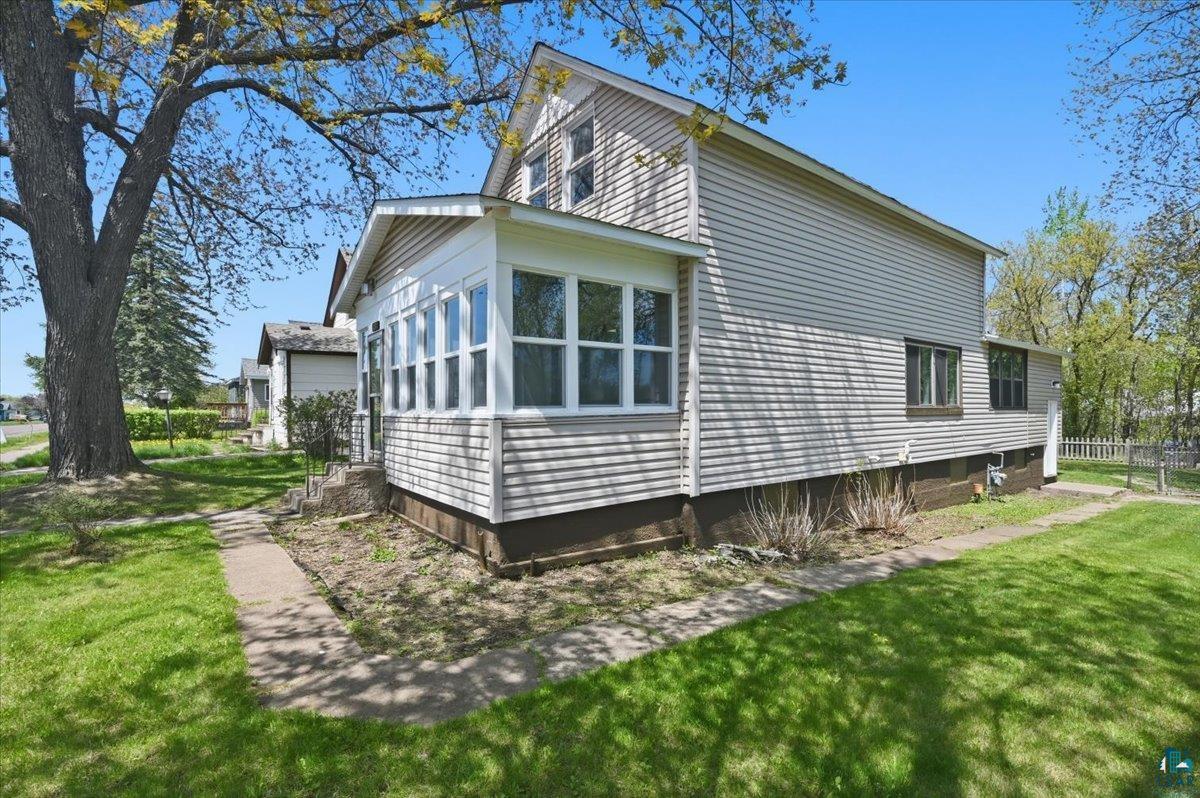 5319 East 3rd Street Superior, WI 54880 - Photo 3 of 33 Exterior featuring light-toned horizontal siding, a sunroom with multiple windows, and a mature tree