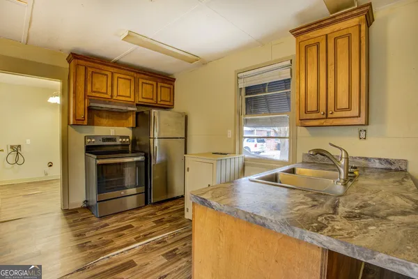a kitchen with granite countertop a sink stove and refrigerator
