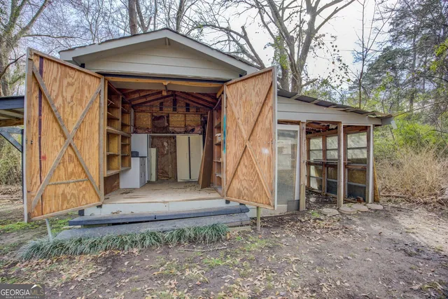a view of wooden house with a small yard and large trees
