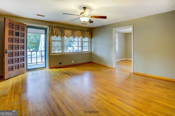 an empty room with wooden floor and windows