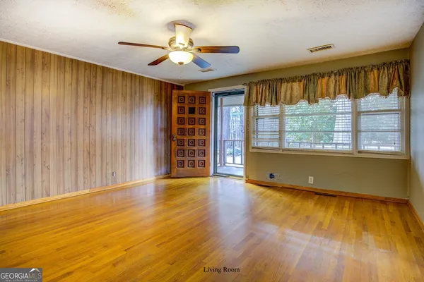 a view of an empty room with a window and wooden floor