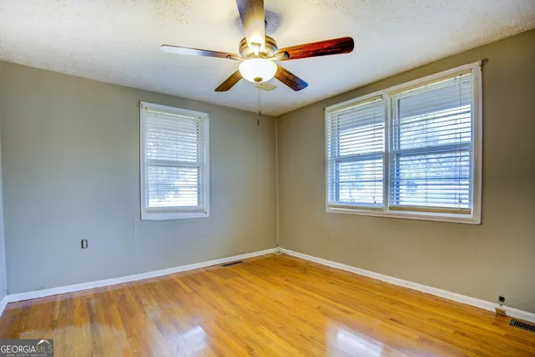 a view of an empty room with window and chandelier fan