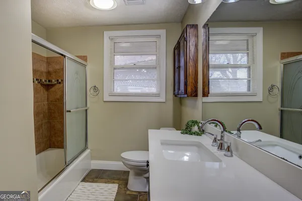 a bathroom with a sink a toilet and shower