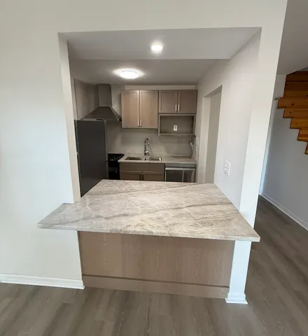 a room with kitchen island stainless steel appliances a sink stove and refrigerator